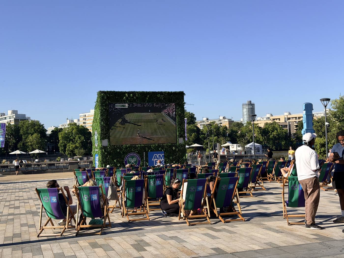 Deckchairs in a sunny square facing a large outdoor screen